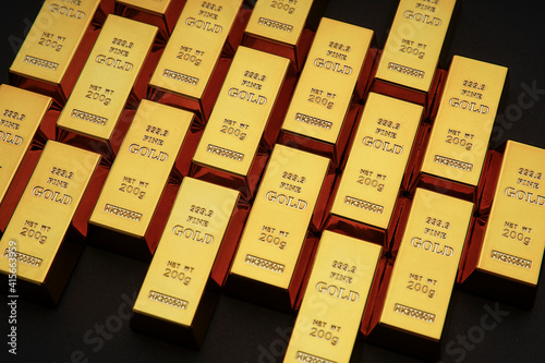 Gold bars next to each other on a black background. Shiny precious metal for investment or as a reserve. Place for text.