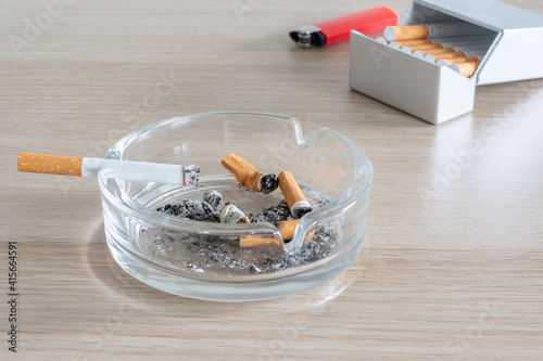 Foto Cendrier en verre avec une cigarette allumée, étui à cigarettes et briquet