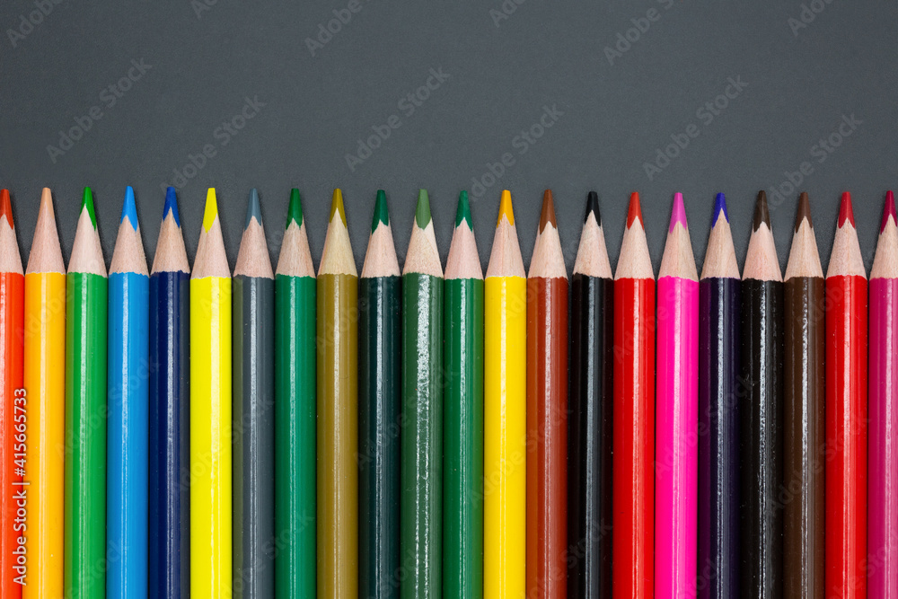 large set of crayons lined up in different colors with dark background for school and arts with copy space for free text large set of crayons lined up in different colors with dark background for school and arts with copy space for free text
