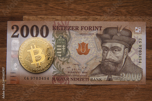 Hungarian forint 2000 forint banknote Gábor Bethlen portrait. Brown wooden table. Next to it is a gold bitcoin digital cryptocurrency coin. Bank image and photo. photo