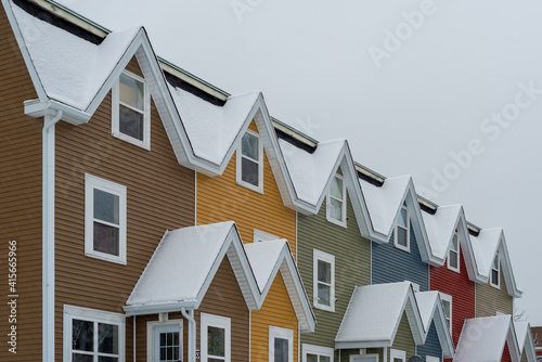 St. John's, Newfoundland, Canada - February 2021: Street View of multiple colourful row houses in downtown St. John's. The buildings have flat roofs, small windows, wood siding and multiple layers.