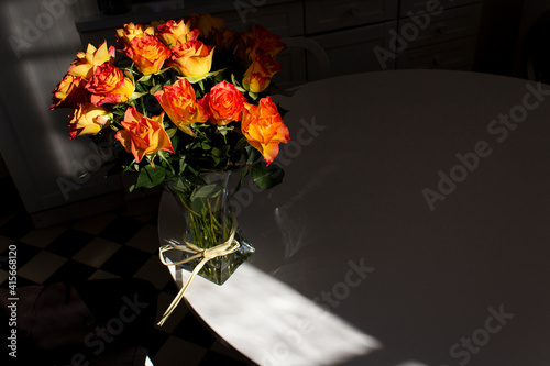 Orage color roses bouquet into glass vase on white home table into morning light floral present love romance concept