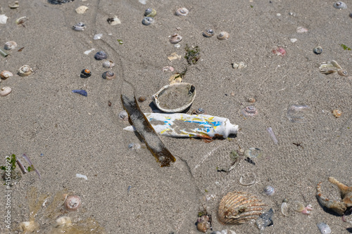 Used Tooothpaste tube discarded on shells beach ecosystem,sea coast pollution contamination