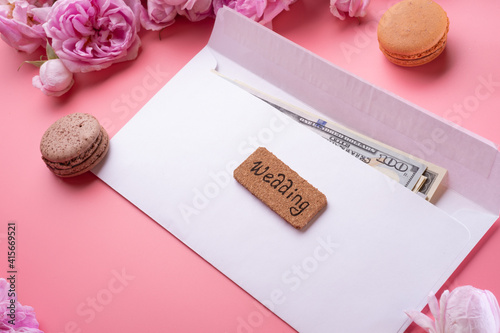  white envelope with cash around roses and macaroons against  pink background. life style concept photo