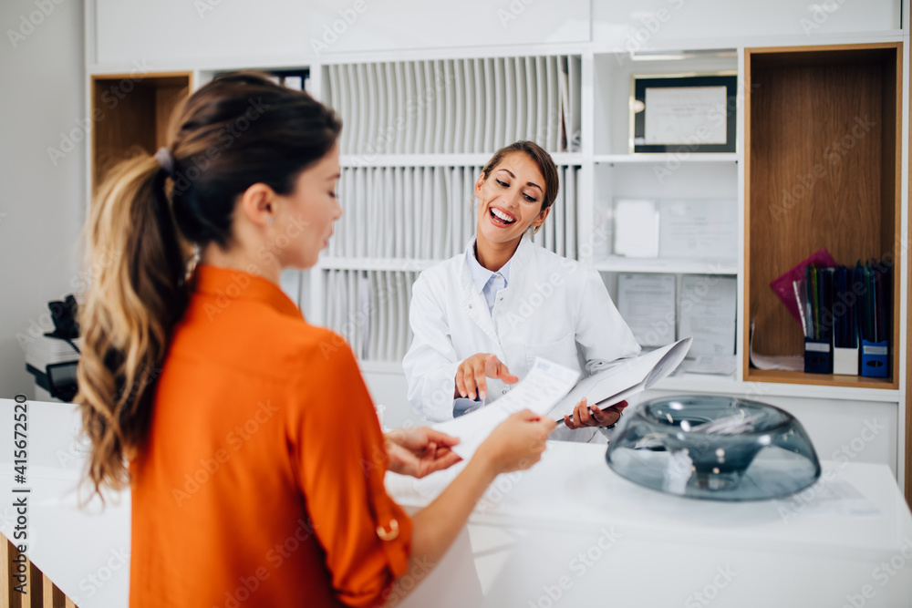 Young female practitioner or nurse working at clinic reception desk. Young female practitioner or nurse working at clinic reception desk.