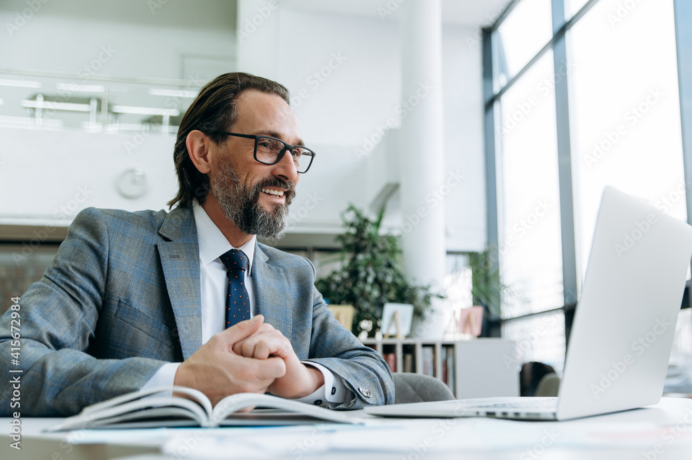 Successful middle aged male manager or ceo talks with colleagues at online conference, planning new project. Elegant businessman is using laptop, communication concept Successful middle aged male manager or ceo talks with colleagues at online conference, planning new project. Elegant businessman is using laptop, communication concept