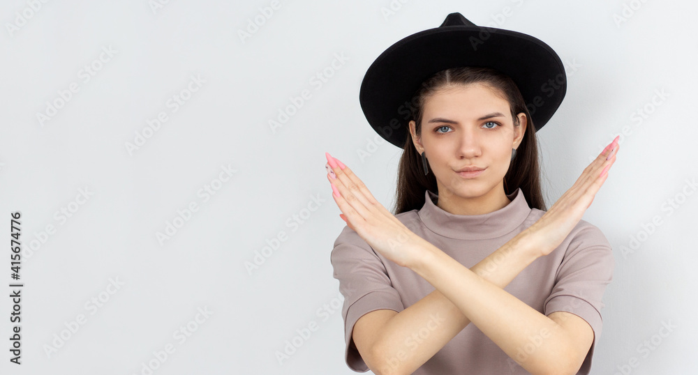 Serious Young brunette woman keeps two arms crossed, makes stop or ban gesture, indicates that the passage is closed, denial concept. Studio shot, white background Serious Young brunette woman keeps two arms crossed, makes stop or ban gesture, indicates that the passage is closed, denial concept. Studio shot, white background