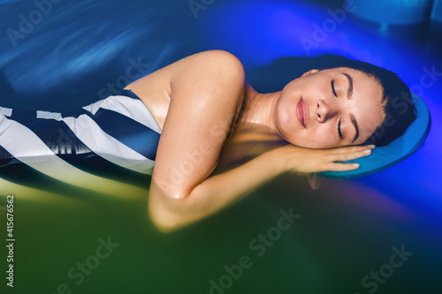 Beautiful woman floating in tank filled with dense salt water used in meditation  therapy  and alternative medicine. .
