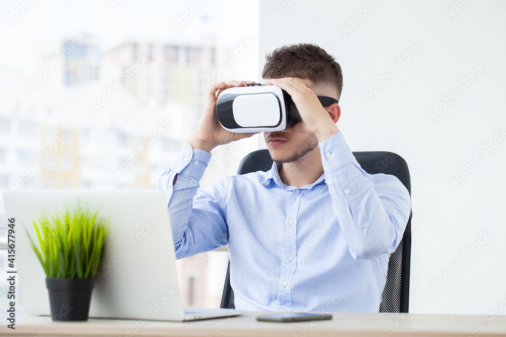 Young man wearing virtual reality goggles in modern coworking studio. Young man wearing virtual reality goggles in modern coworking studio.