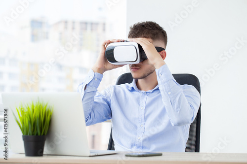 Young man wearing virtual reality goggles in modern coworking studio.