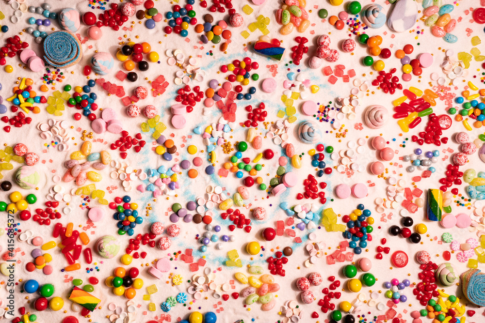 Candy in variety of colour, shape, size and flavours mixed on the table with real white sugar. International Candy Day background. Sweet stock of snack, chocolates, caramels, candy, and jelly beans.