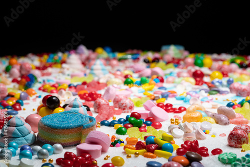 Random candy, shallow depth of field. Mixed colorful lollipops and gums, unicorn poop marshmallows explosion. Variety flavoured confetti of sweets, sugar and cake icing, caramel feast celebration