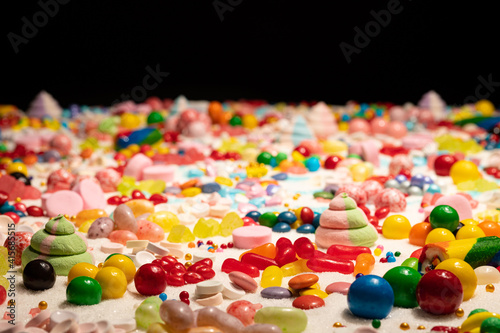 Confectioner’s close up of jelly beans, colorful chocolate coated candy, various flavours mixed sweets, marshmallow, snack, caramels, swirls, sugar and cake sprinkles. Candy land explosion dream.