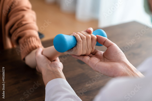 The doctor performed hand physical therapy for the patient with dumbbells.