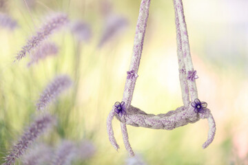 A swing for newborn baby photographers.  Colors are yellow, green and purple.  Photography backdrop.