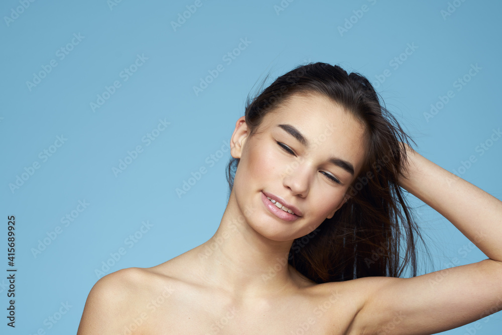 brunette with bare shoulders cosmetics close-up skin care blue background brunette with bare shoulders cosmetics close-up skin care blue background