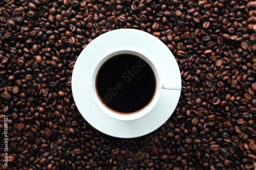White plate, cup of coffee on a bunch of roasted coffee beans background