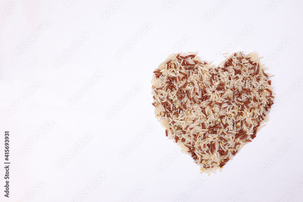 Mixed low glycaemic index healthy rice grain basmati millet buckwheat red rice hart shape on white background