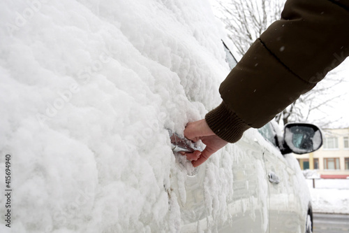 Man hand opens frozen car door in snowy winter. © Yekatseryna