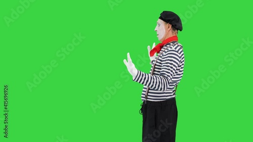 Mime playing a pantomime performance walking and opening imaginary door on a Green Screen, Chroma Key. photo