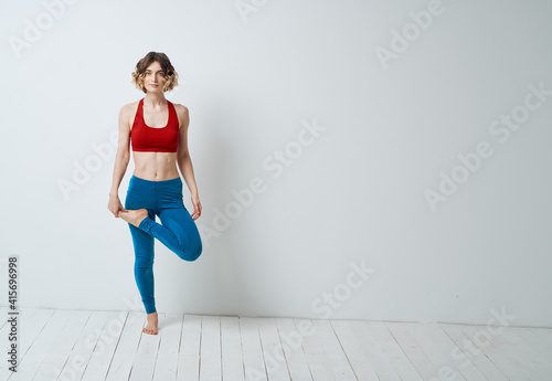 woman in blue leggings doing sports on a light floor indoors in full growth