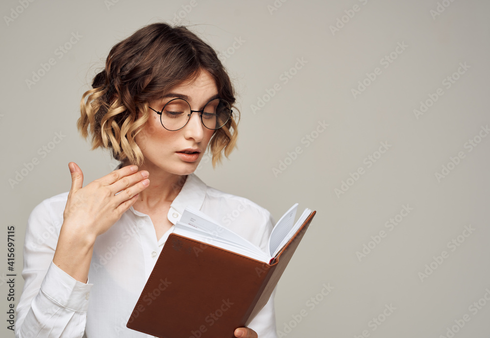 woman with notepad on gray background indoors gesturing with hands work office education woman with notepad on gray background indoors gesturing with hands work office education