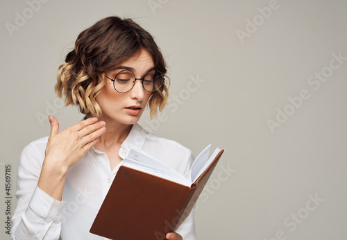 woman with notepad on gray background indoors gesturing with hands work office education