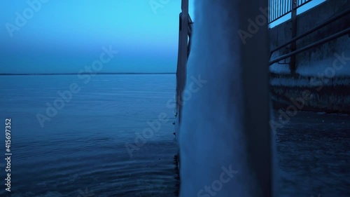 A desolate ice-covered bathing ramp leading down into the cold water during winter photo