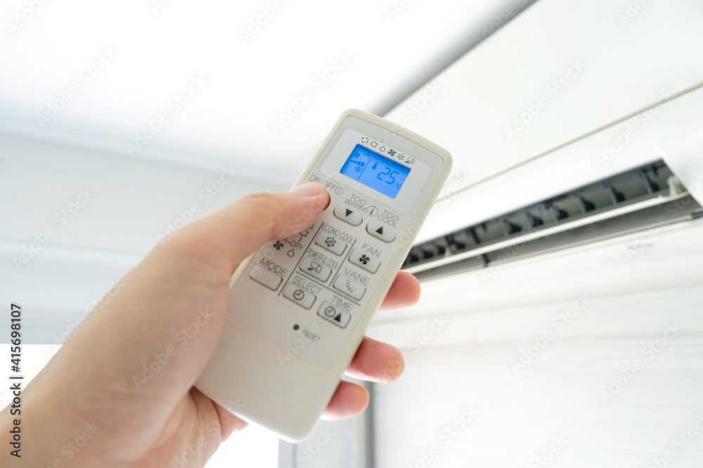 Man's hand using remote control open The air conditioner is cooled to 25 degrees Celsius in his bedroom. Health concepts and energy savings Man's hand using remote control open The air conditioner is cooled to 25 degrees Celsius in his bedroom. Health concepts and energy savings