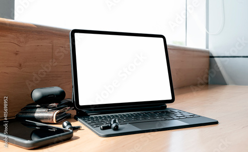 Mockup blank screen tablet with magic keyboard on wooden counter table in cafe.