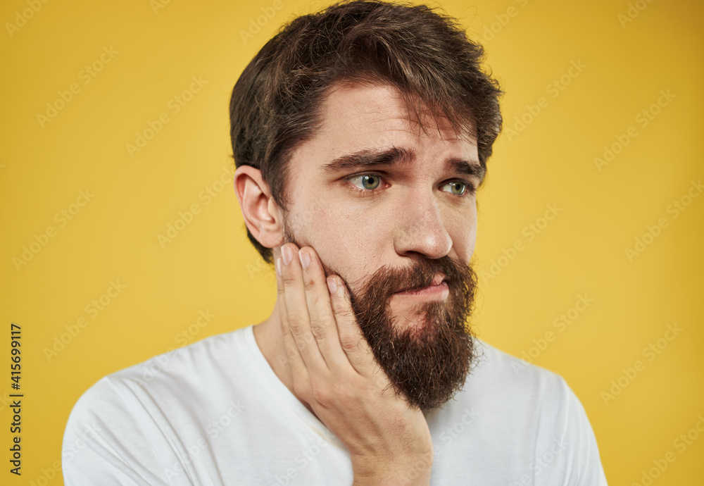 man on a yellow background in a white t-shirt sad face beard model
