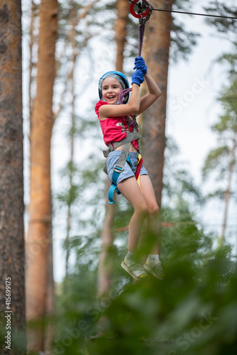 girl in equipment overcomes an obstacle in a rope park at a height