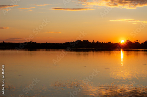 A colorful sunny sunset is reflected on the surface of the calm lake. © Анатолий Савицкий