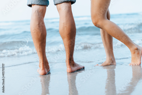 Legs of couple stand together on beach. Man and woman in love.