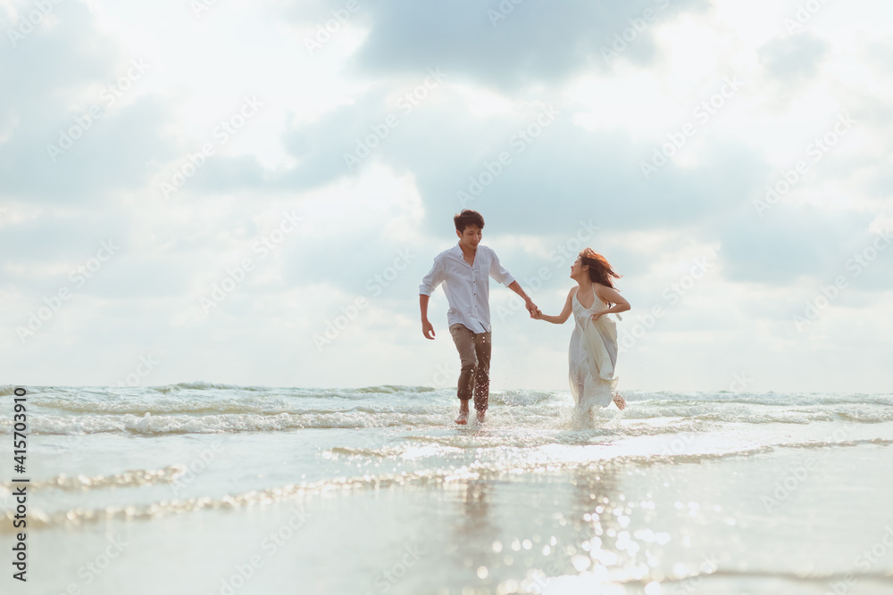 Fototapeta premium Love young couple holding hands and running on the beach. Holiday and vocation concept.