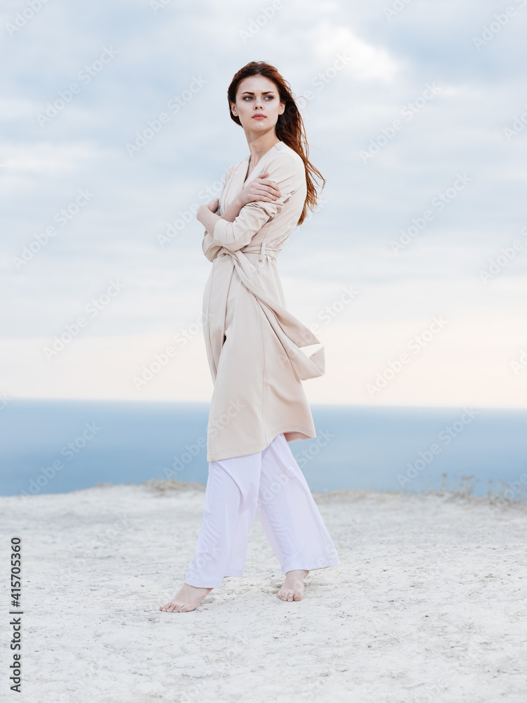 woman in light trousers and a sweater travels in the mountains on nature ocean in the background woman in light trousers and a sweater travels in the mountains on nature ocean in the background
