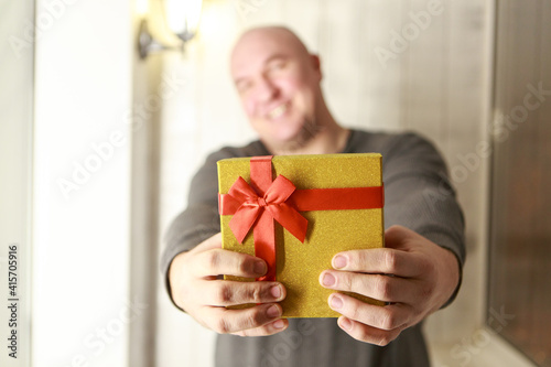 A man gives a gift to a woman. Handing over a shiny box. The concept of a holiday, a surprise