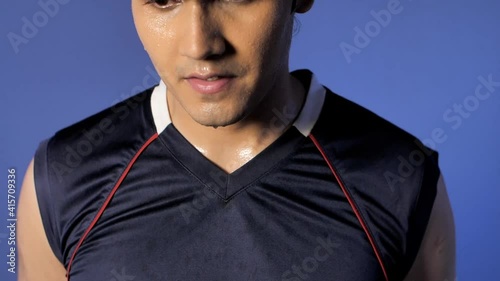 A perspiring youngster wearing black sleeveless sportswear standing indoors . Exhausted athlete with sweat drops on face after an intense exercise session - healthy active lifestyle photo