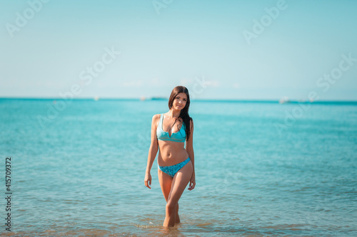 Summer. A young pretty woman poses standing at the ocean. The concept of summer holidays. Copy space