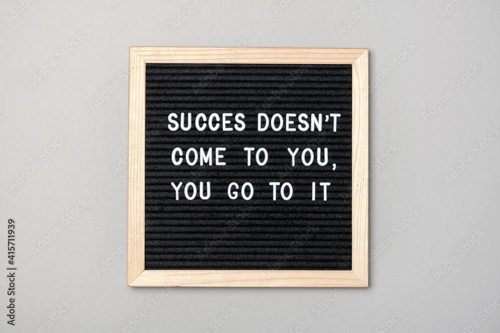Success doesn't come to you, you go to it. Motivational quote on black letter board on gray background. Concept inspirational quote of the day. Greeting card, postcard