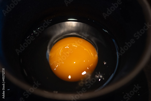 A raw egg in in small black bowl