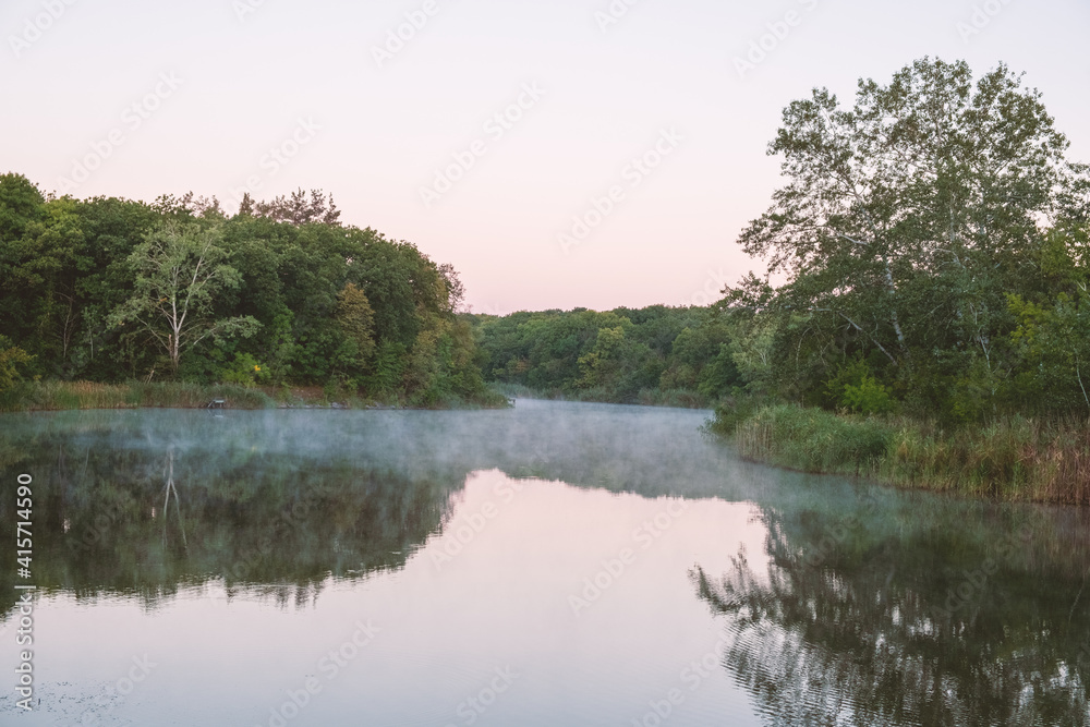 Fog above the river surface on a summer calm morning, trees reflected in the water. Silence and natural beauty. Nature. Landscape - Foggy river