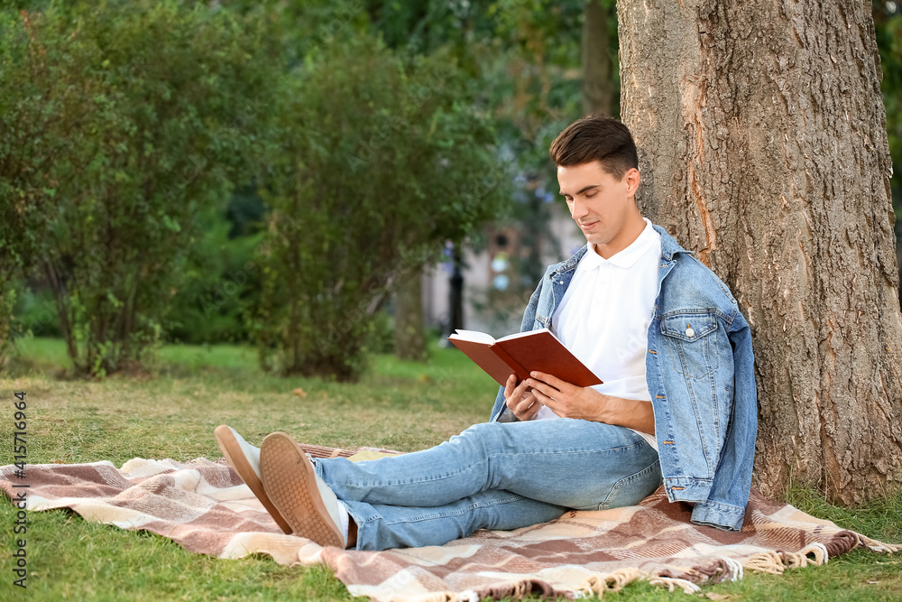Young man reading book in park Young man reading book in park