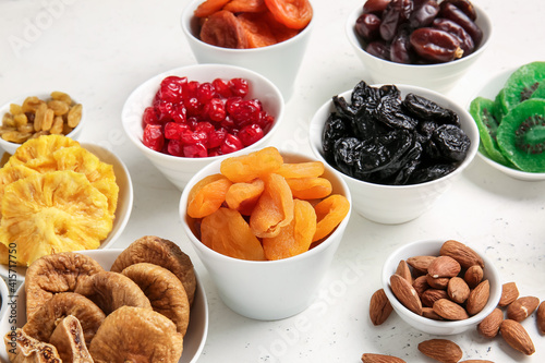 Fototapeta Naklejka Na Ścianę i Meble -  Bowls with different dried fruits and nuts on light background
