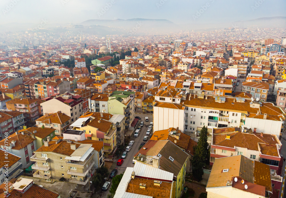 Cityscape of Balikesir town with houses and mosque in light fog as seen from drone in winter day, Turkey.