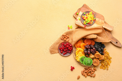 Plates with different dried fruits and nuts on color background
