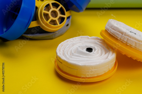 New replacement filters and Industrial respirator on yellow background.