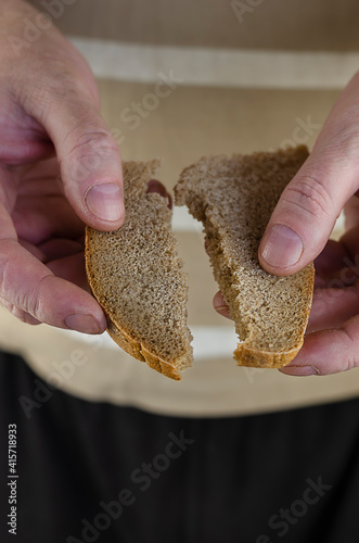 A man's hand splits a slice of rye bread in two.