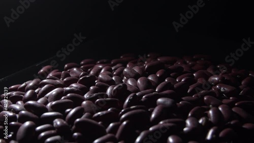 Red beans in a black tray gyrating with a intimate light, rotation photo