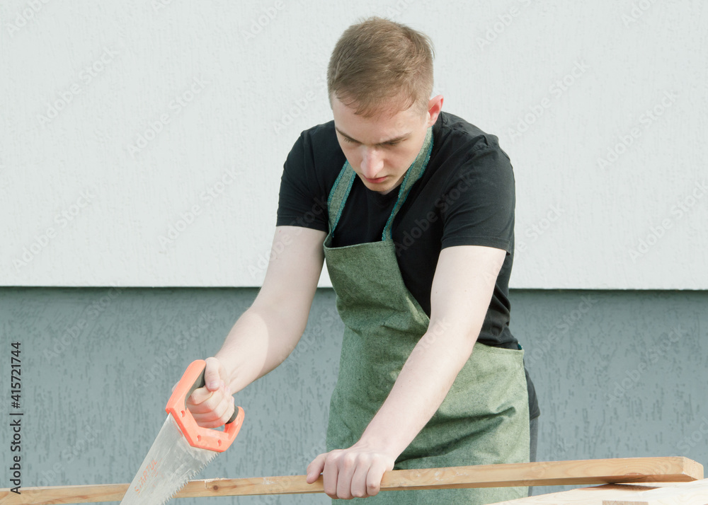 Carpenter working with wooden plank. The young man is working near his house. Carpenter working with wooden plank. The young man is working near his house.